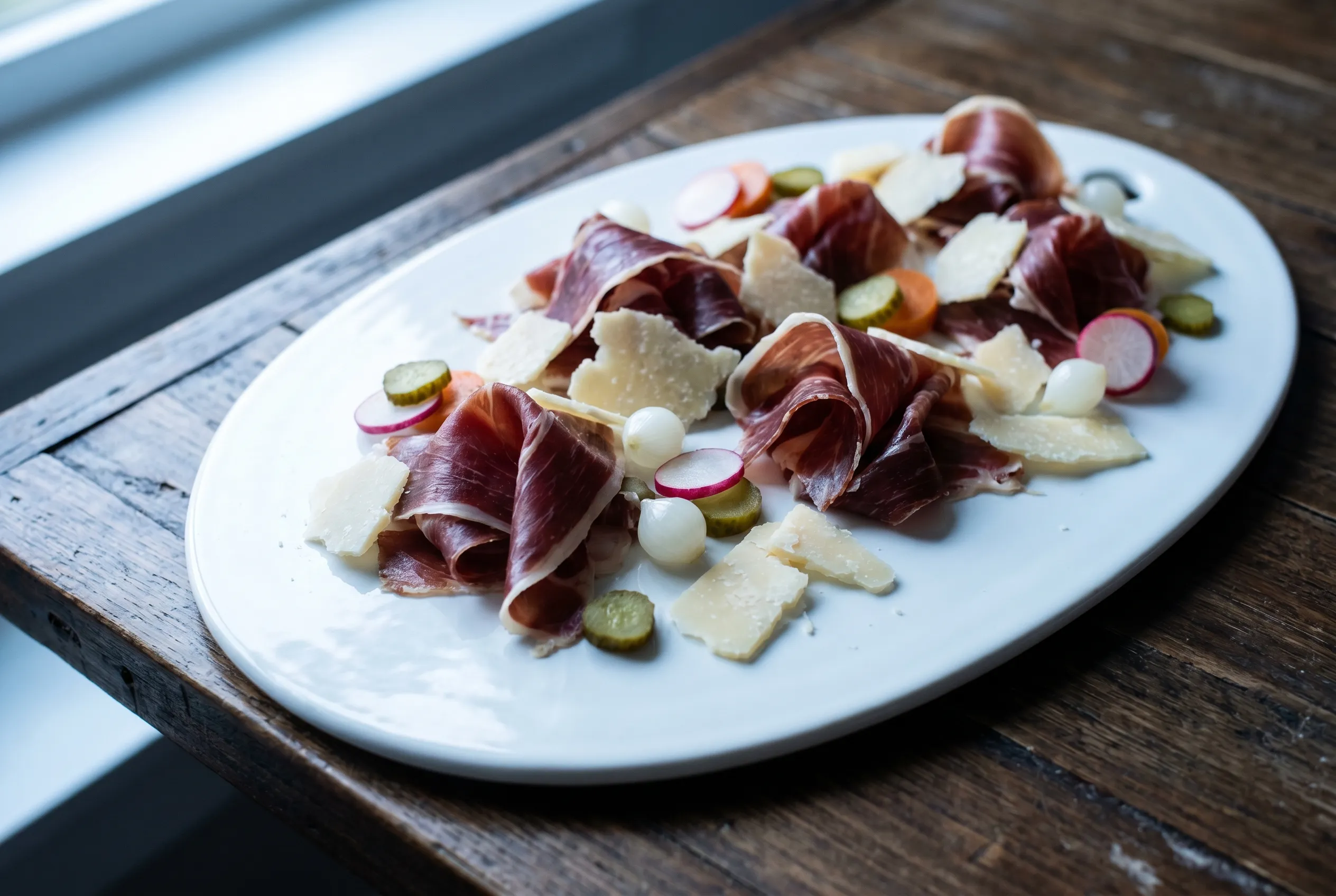 Assiette de pata negra, copeaux de parmesan et pickles de légumes